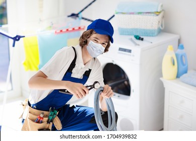 Plumber Emergency Service During Coronavirus Outbreak. Technician In Face Mask Repairing Broken Washer. Maintenance Of Home And Household Appliance In Lockdown And Quarantine. Urgent Repair.

