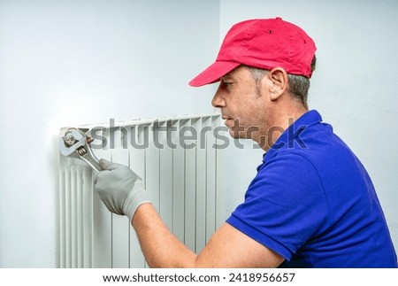 PLUMBER FIXING AND BLEEDING A CENTRALIZED HEATING SYSTEM RADIATOR. MAINTENANCE CONTRACT TO REPAIR HVAC BREAKDOWNS AND WATER LEAKS AT HOME. HOME INSURANCE CONCEPT.