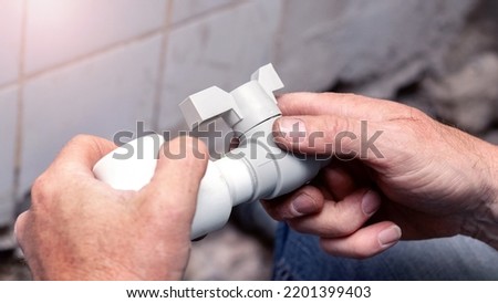 A plumber glues a plastic pipe to a water faucet
