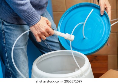 Plumber Hands Are Holding A Round Lid; In His Right Hand He Is Holding The Suction Filter Of The Osmosis Water Purification System.

