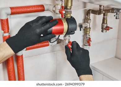 Plumber hands installing circulation pump for a heating system, connecting pipes and control valves