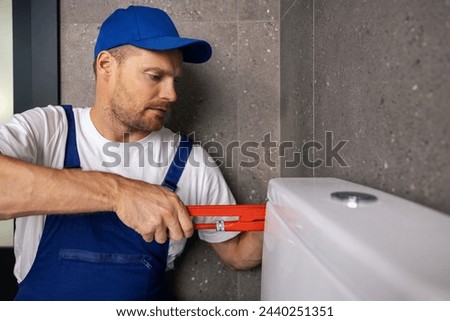plumber handyman working in bathroom installing water closet pipe with wrench