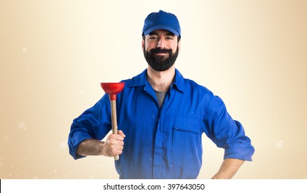 Plumber holding a plunger over ocher background