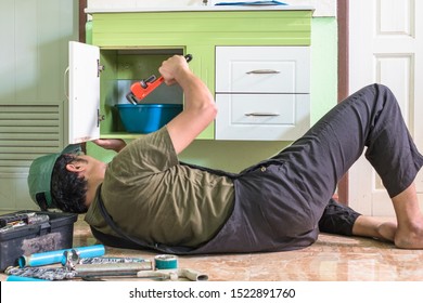 Plumber Holding A Red Pipe Wrench To Fix Or Repair Water Drier For A Wash Basin