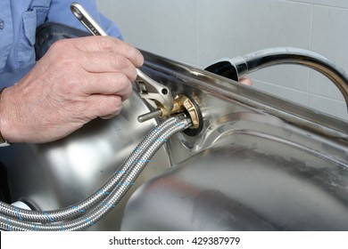 Plumber Installing A Faucet In A Stainless Steel Kitchen Sink