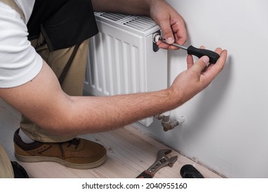 Plumber installing new steel hot water central heating radiator at home