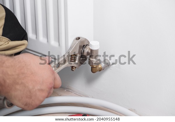 Plumber installing new steel hot water central\
heating radiator at\
home