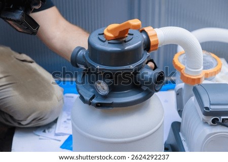 Plumber is installing pool filter system, checking connections gauges in backyard environment.