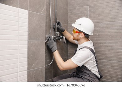 Plumber installing water taps shower stall, work in bathroom. - Shutterstock ID 1670345596