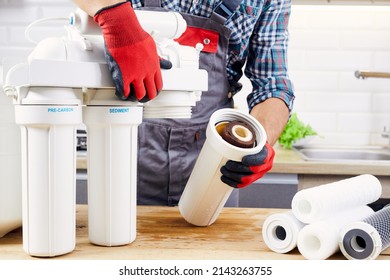 Plumber installs or change water filter. Replacement aqua filter. Repairman installing water filter cartridges in a kitchen. Installation of reverse osmosis water purification system.
