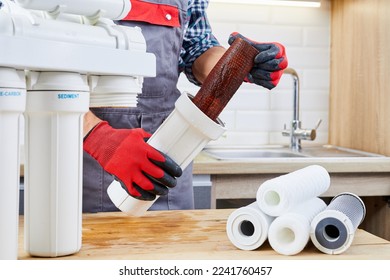Plumber installs or change water filter. Replacement aqua filter. Repairman installing water filter cartridges in a kitchen. Installation of reverse osmosis water purification system.
