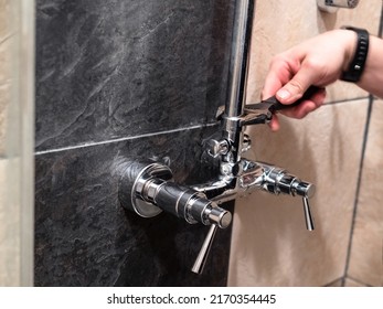 plumber installs shower pipe to faucet valve in shower room at home - Shutterstock ID 2170354445