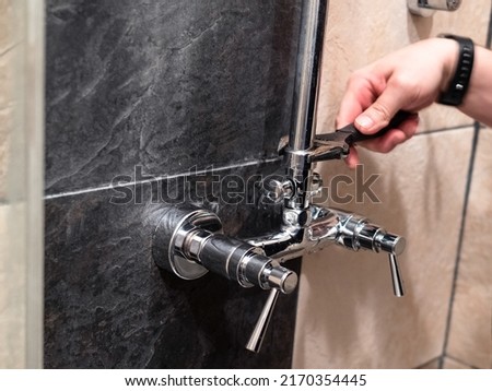 plumber installs shower pipe to faucet valve in shower room at home