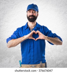 Plumber making a heart with his hands over textured background