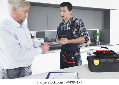 A Plumber Man Communicates With A Client Who Pays For The Work Done. The Old Man Gives The Plumber A Fee. A Black Box For Tools Is Next To It.