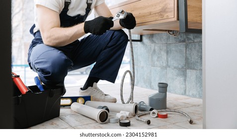 Plumber man fix repair service wraps fluoroplastic sealing material tape around faucet hose. Concept install plumbing in bathroom. - Shutterstock ID 2304152981
