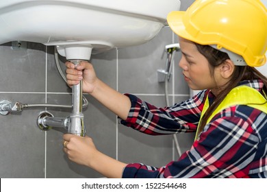 Plumber, Plumbing Specialist Fixing Kitchen Sink. Young Asian Woman Plumber Checking Or Repairing A Leaky Drain In Bathroom. Construction, Engineering, Repair, Building And Home Concept