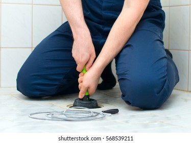 Plumber repairing bathroom with hand plunger.