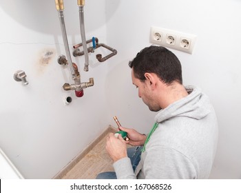 Plumber Repairing An Electric Boiler Inside Home