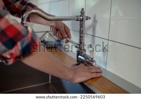 Plumber repairing a faucet in the kitchen