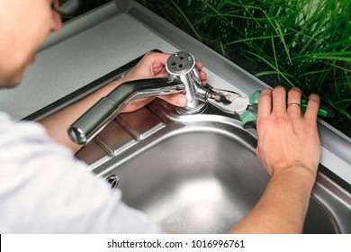 Plumber Repairing The Faucet Of A Sink In Kitchen, Man Repair And Fixing Leaky Old Faucet, Cartridge Or Mixer Of The Faucet, Concept Of Repair And Technical Assistance