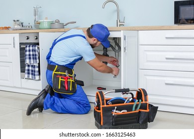 Plumber repairing sink in kitchen - Powered by Shutterstock