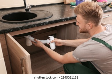 Plumber Repairing Sink In Kitchen