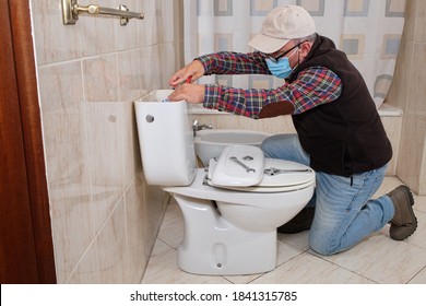 Plumber Repairing A Toilet With A Mask, Coronavirus Concept