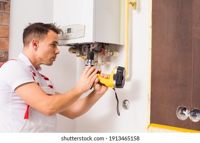 The Plumber Repairs A Boiler At The Kitchen