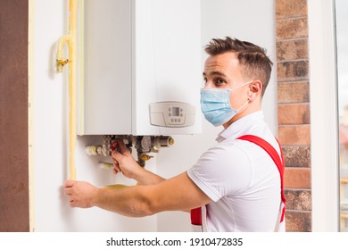 The Plumber Repairs A Boiler In A Medical Mask