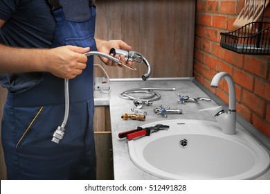 Plumber replacing faucet in kitchen, close up view - Powered by Shutterstock