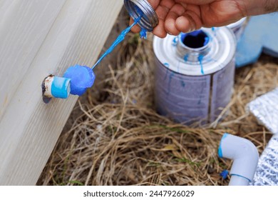 Plumber sealing a pvc plastic pipe with glue before gluing it