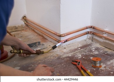 plumber soldering a copper pipe as part of a heating system