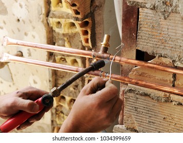 A plumber soldering pipes of copper whit torch, total reform of a house - Powered by Shutterstock