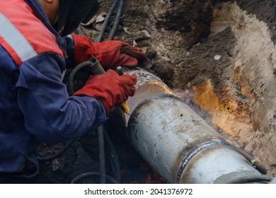 Plumber standing in pit is engaged in elimination of communal accident outdoors. Utility worker fixing broken water main. Welding work to replace rotten elements of water pipe. Sewerage pipe repair
