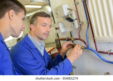 Plumber Teaching Trainee To Connect Radiator