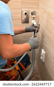 Conexión de la manguera de drenaje de apriete de fontanero de la lavadora con destornillador en el baño moderno.