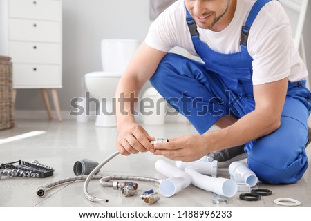 Plumber with tools working in restroom