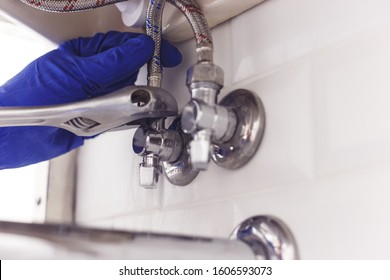 Plumber Turns Nut On Angle Valve Under Wash Basin Using Spreading Wrench.