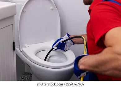 plumber unclogging blocked toilet with hydro jetting at home bathroom. sewer cleaning service - Shutterstock ID 2224767439