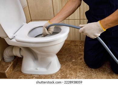 plumber unclogging blocked toilet with hydro jetting at home bathroom. sewer cleaning service - Shutterstock ID 2228938059