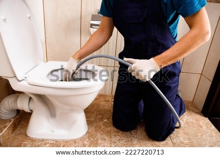 plumber unclogging blocked toilet with hydro jetting at home bathroom. sewer cleaning service Foto d'archivio © 