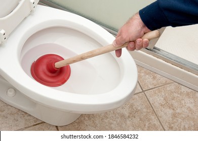 A plumber uses a plunger to unclog a toilet.