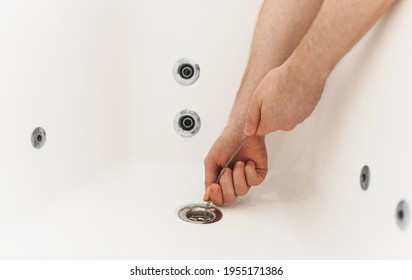 Plumber Using Drain Snake To Unclog Bathtub.