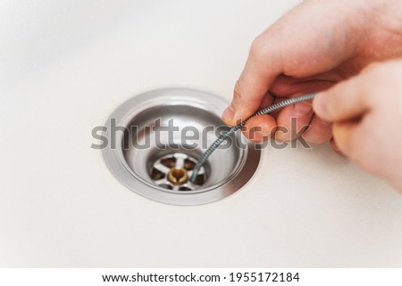 Plumber using drain snake to unclog kitchen sink.