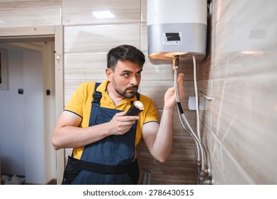 Plumber using flashlight is inspecting a water heater in a bathroom