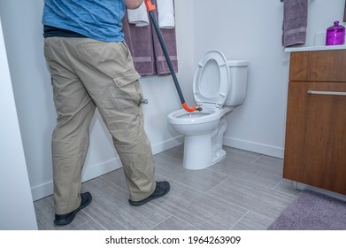 Plumber Using A Hand Auger To Snake A Toilet