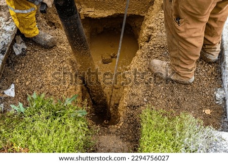 A plumber using hydro excavator to repair a leaking main water line. An excavating crew using a hydro vac to gain access to a leaking main water line.  ストックフォト © 
