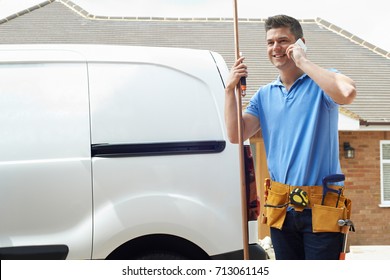 Plumber With Van Making Call On Mobile Phone Outside House