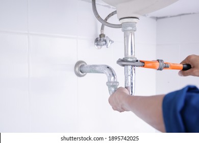 Plumber working in the bathroom, plumbing repair service, repairing leaking sinks with adjustable wrench, assemble and install concept. - Shutterstock ID 1895742025